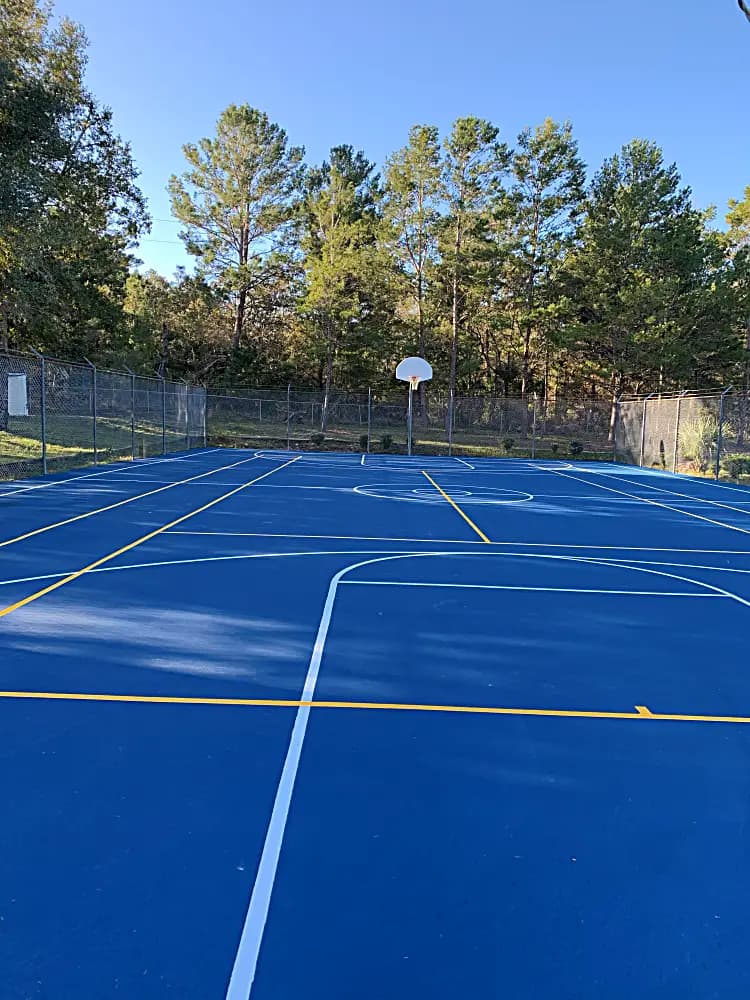 Completed basketball court with blue surface and fresh striping