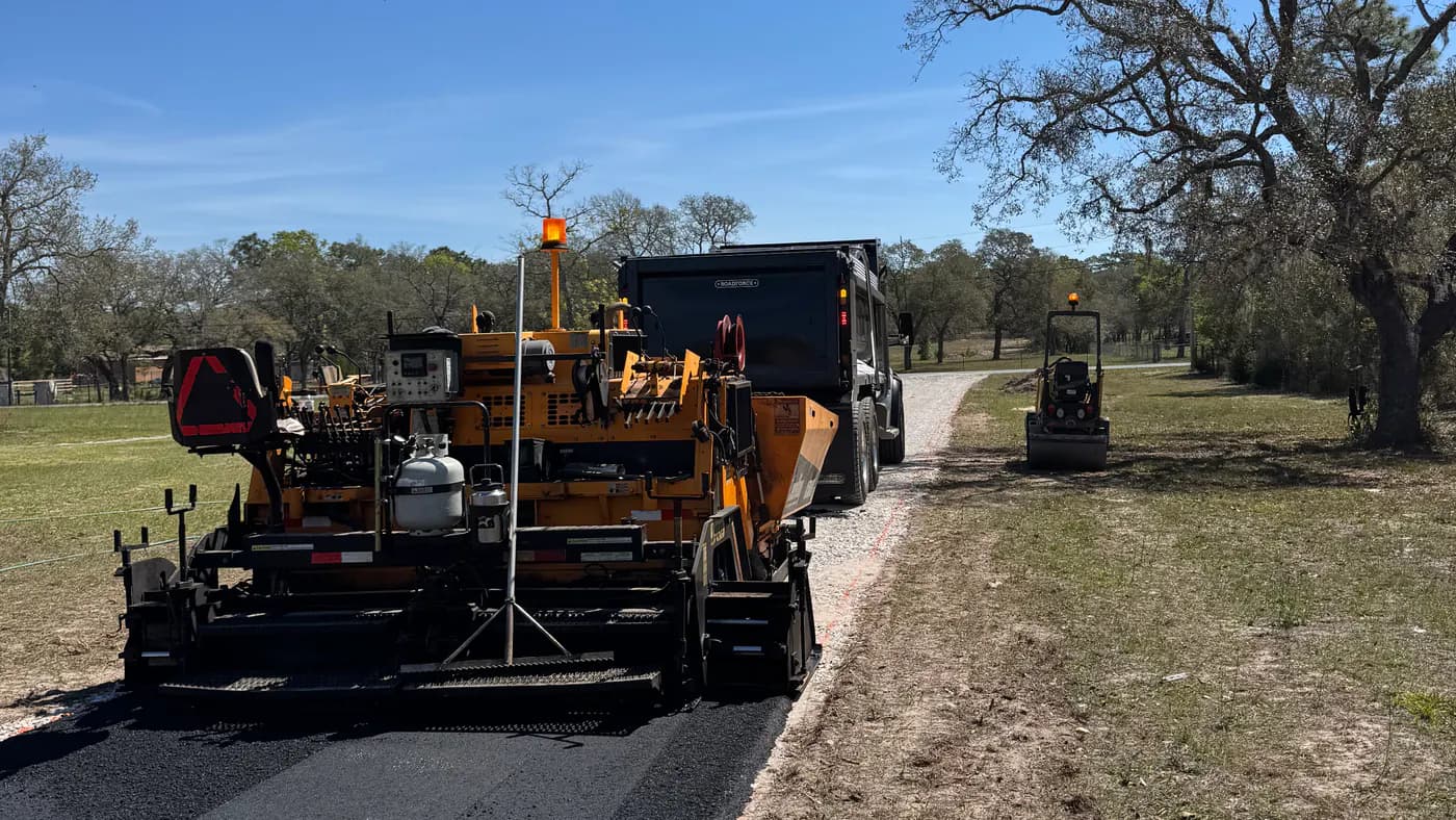 Paving equipment placing asphalt on a long private driveway
