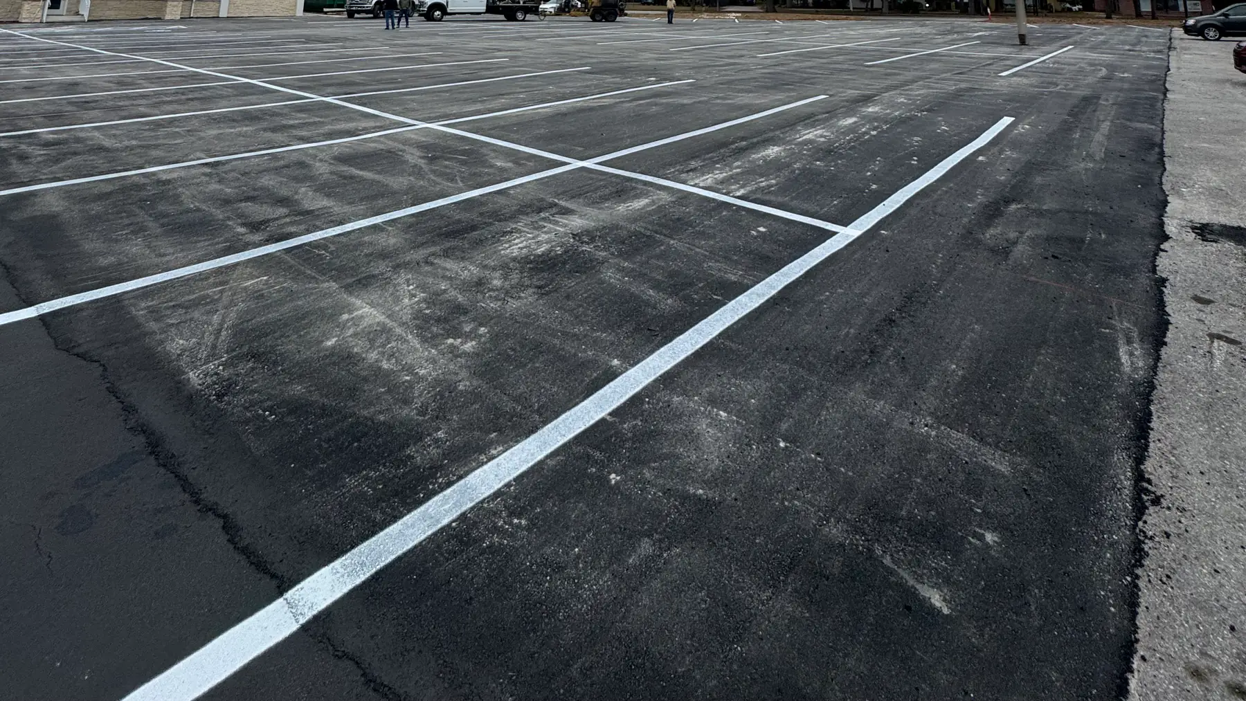 Fresh white parking-space striping across a commercial asphalt lot