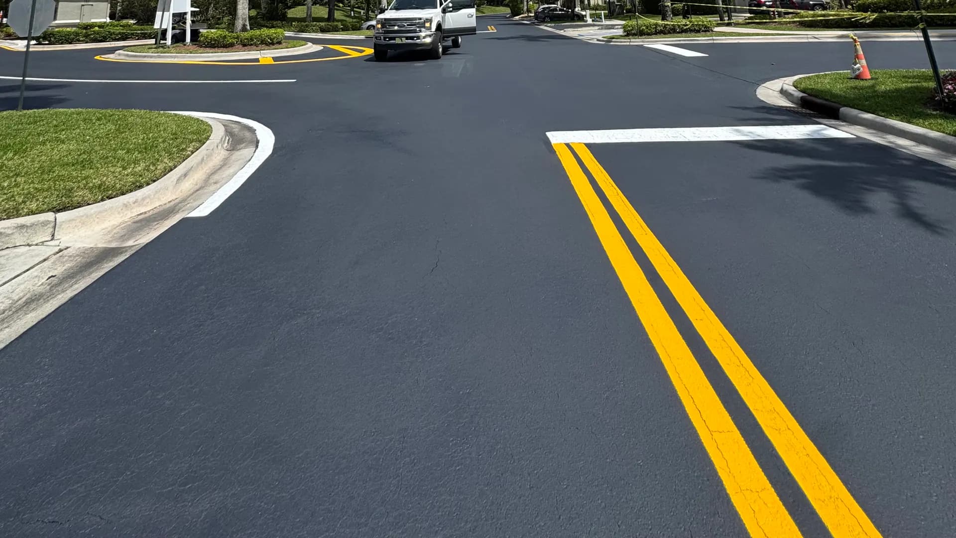 Fresh asphalt and roadway markings bordered by concrete curbs