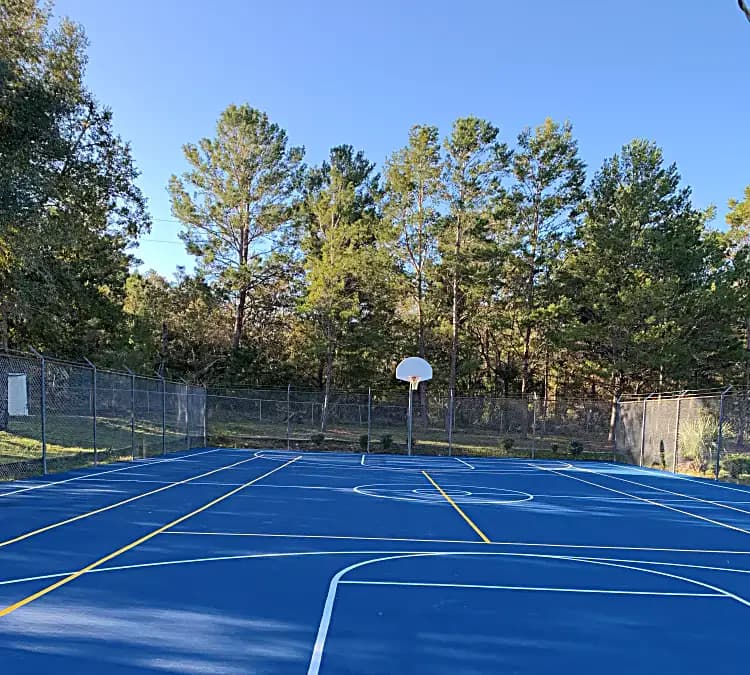 Completed blue outdoor court with fresh basketball and multi-sport line markings